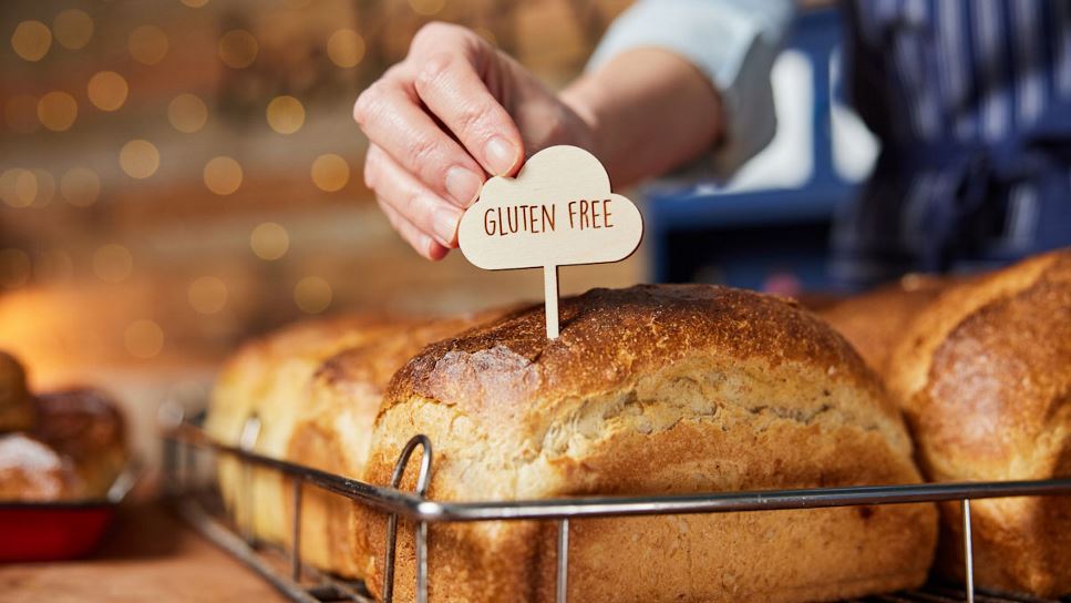 A sales associate sticks a "gluten-free" label into bread.