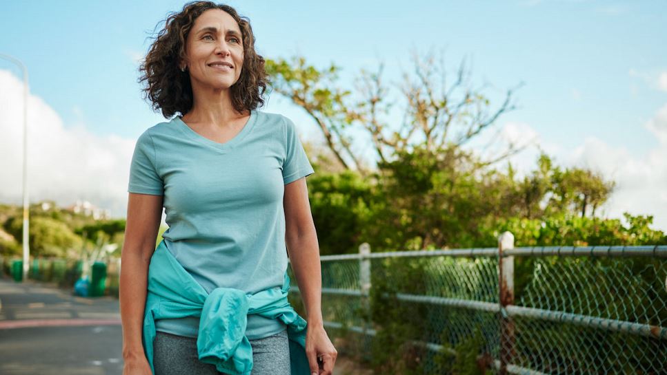A smiling, middle age woman is walking.