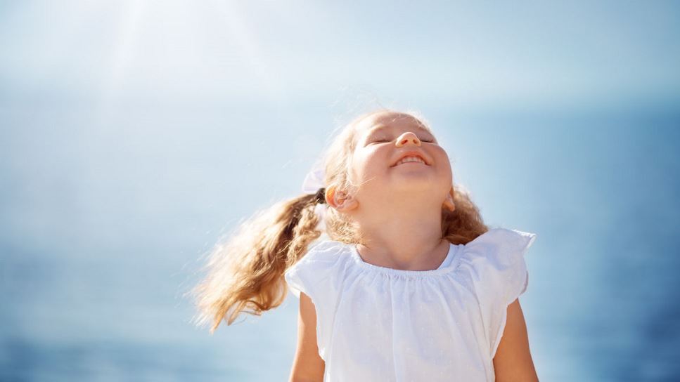 A young girl smiles and basks in the sunshine.